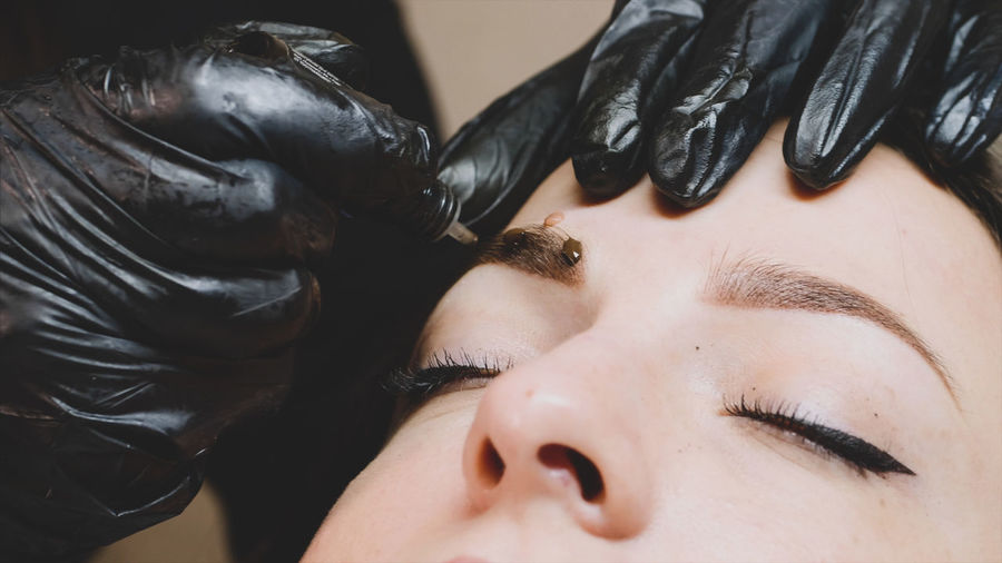 Cropped hands of beautician coloring woman eyebrow