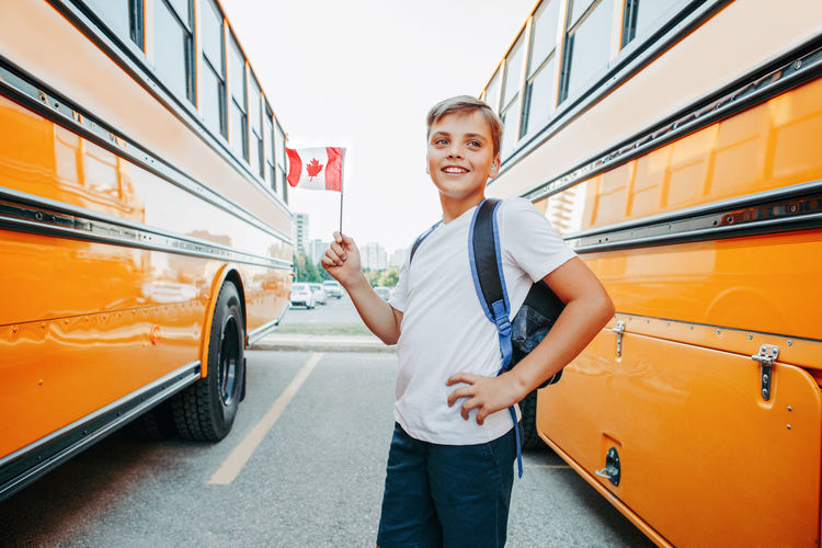 Smiling boy with flag standing by bus