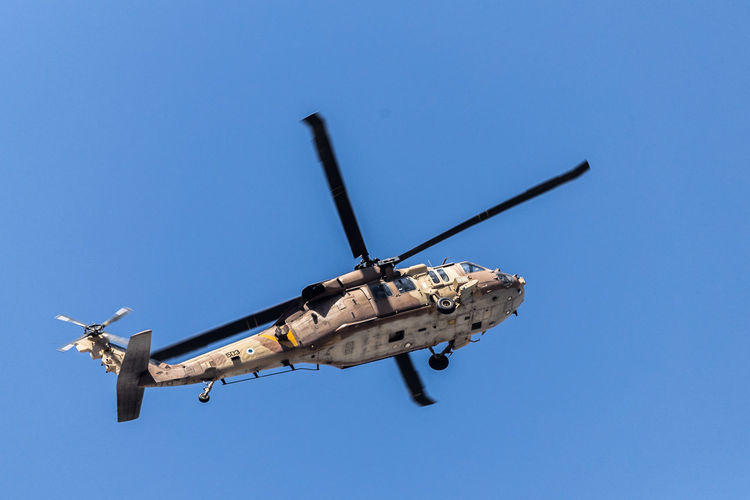 Low angle view of military helicopter flying against clear sky