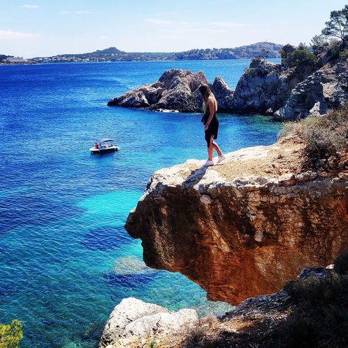 Woman standing on cliff by sea