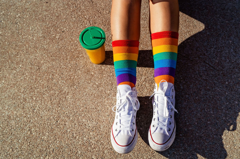 Top view of legs in bright colorful rainbow socks at sunlight . generation z lifestyle, pride month