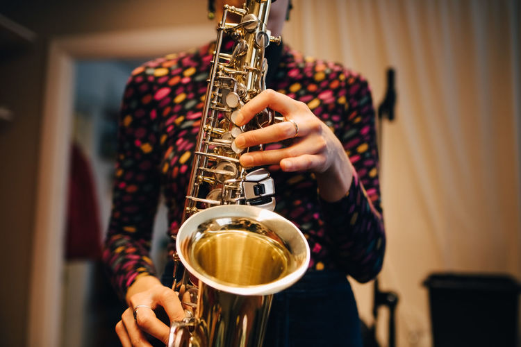 Midsection of woman playing saxophone while practicing at studio