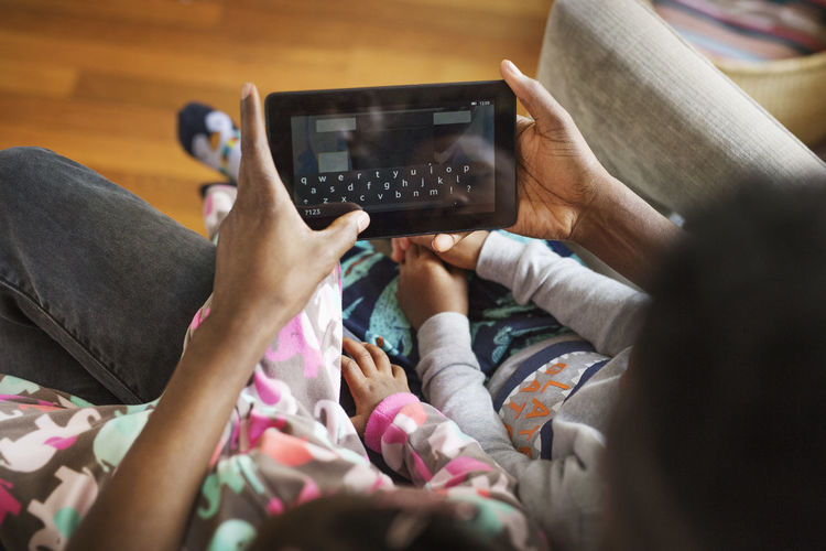 Overhead view of father using tablet computer with children at home