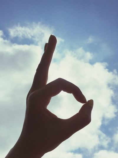 Close-up of woman showing ok sign against sky