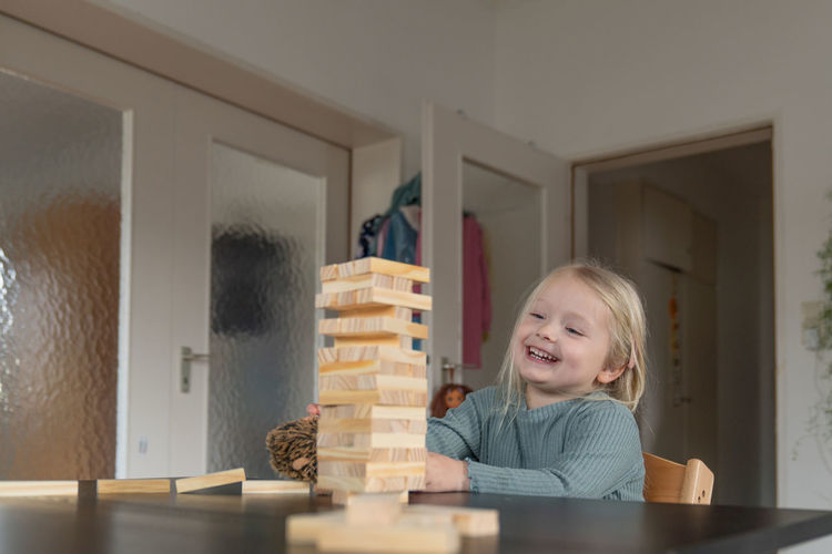 Toddler girl looking happily on the just built tower