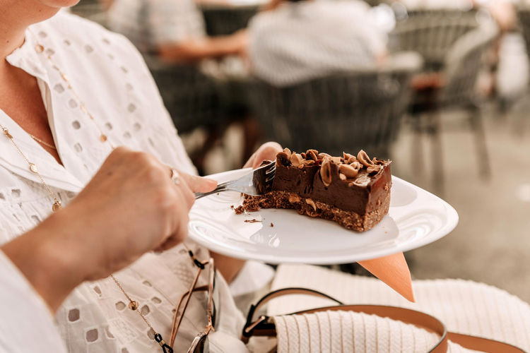 Close-up photo of woman eating delicious cake in cafe