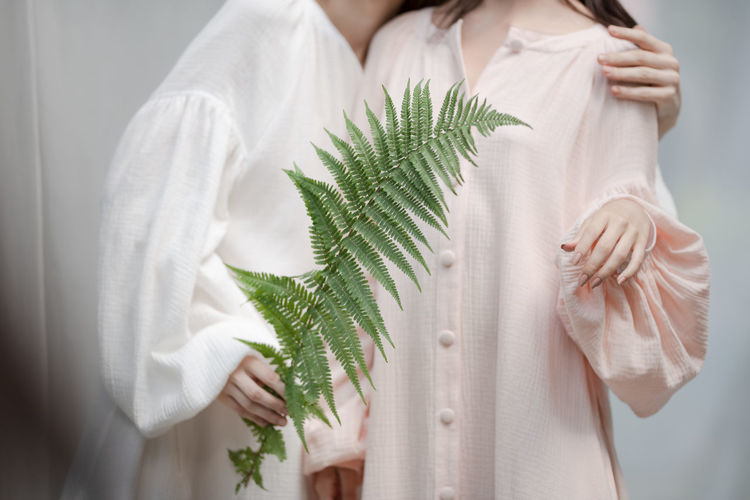 Midsection of women standing with plant