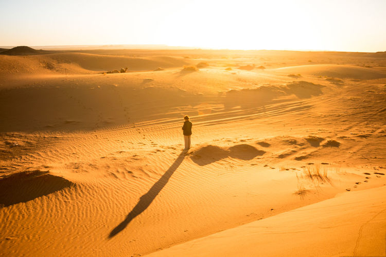 Woman alone in the desert between dunes at sunrise