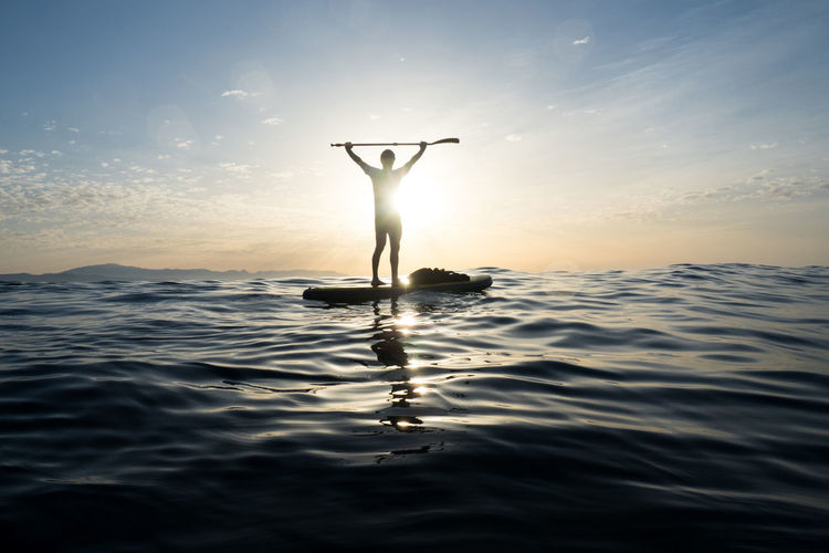 Concept: victory and happiness. man on a paddle surf board. in t person