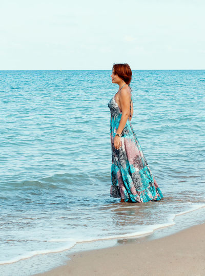Young woman in a long dress walking on the beach