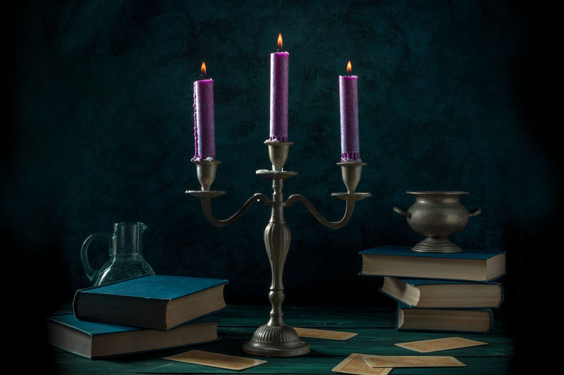 Close-up of illuminated candles on table against black background