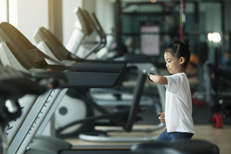 Side view of girl looking at smartwatch in gym