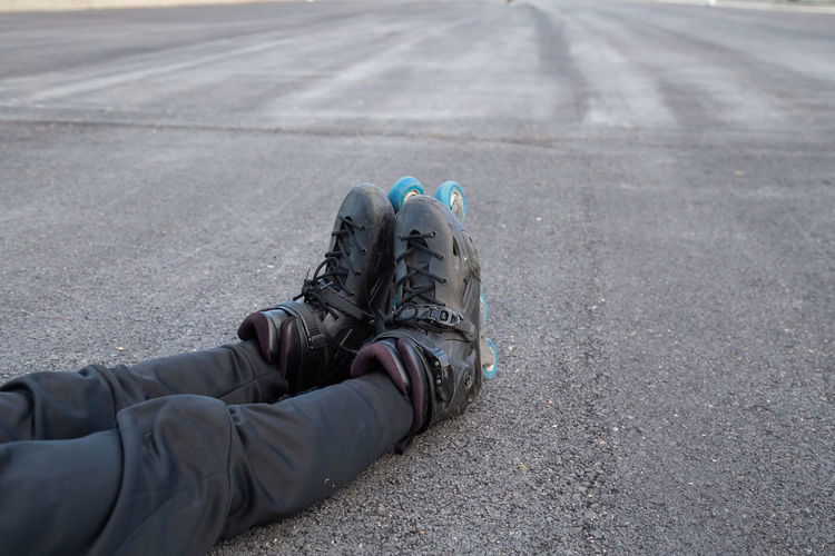 Low section of person wearing inline skating sitting on road