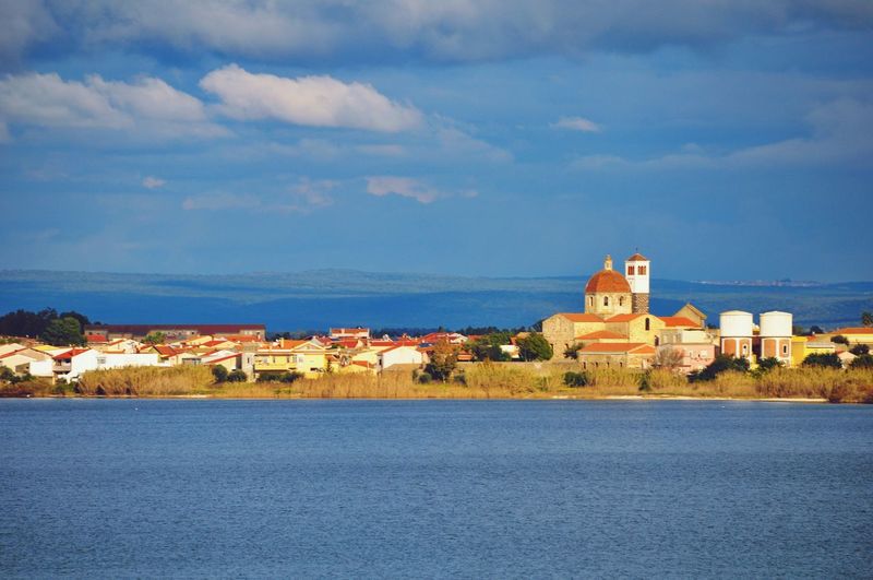 Buildings by sea against sky in city