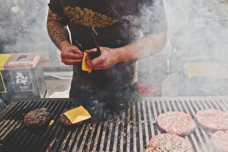 Men cooking hamburger on barbecue