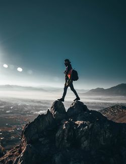 Man standing on rocky mountain against sky