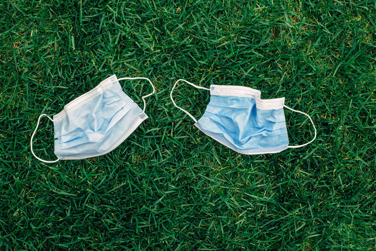 Two used sanitary masks lying on grass ground. disposable recyclable face mask flat lay. 