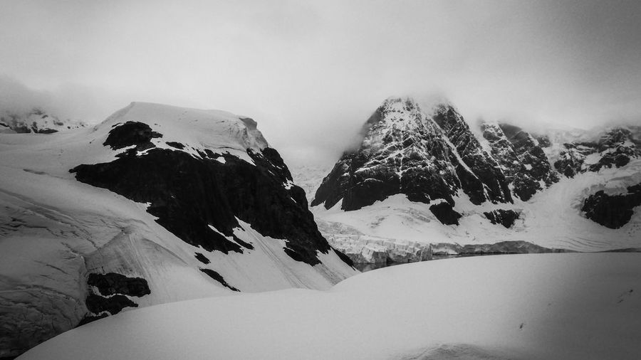Black and white photo of glacier against snowcapped mountain in antarctica