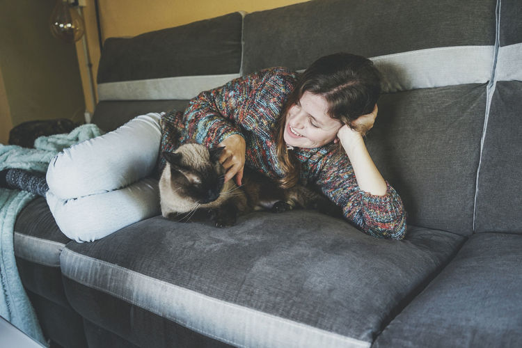 Happy woman playing with cat at home