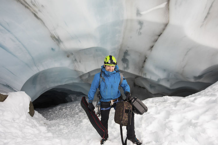 Scientist carries video gear from glacier cave for climate research