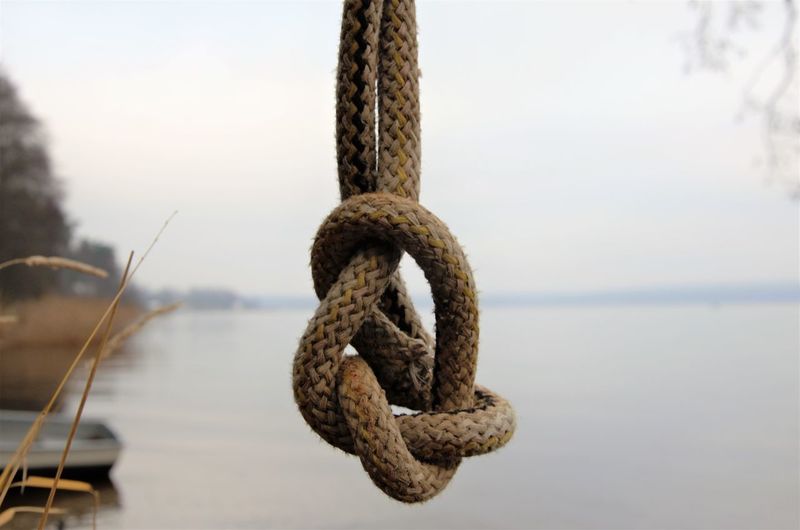 Close-up of rope tied on bollard against sky