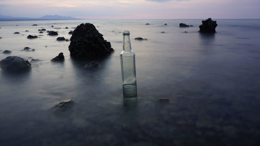 Long exposure shot of empty bottle at calmness beach in lombok, indonesia on sunset time