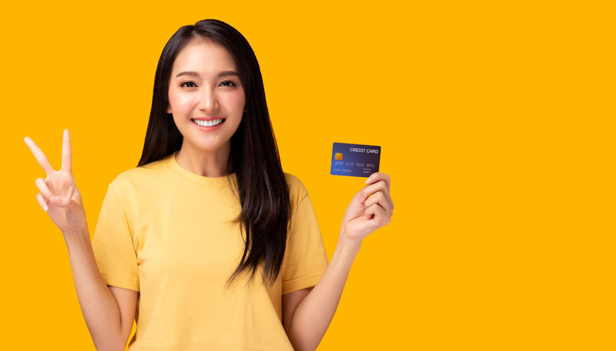 Portrait of a smiling young woman against yellow background