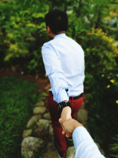 Gay man holding hand of partner at park