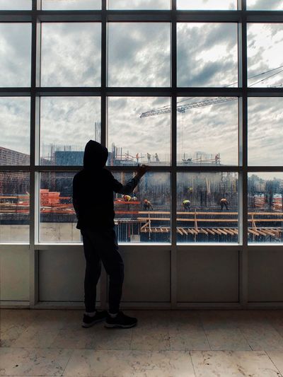 Rear view of man looking at construction site through window