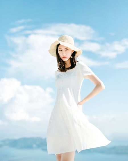 Portrait of beautiful woman wearing hat while standing against sky