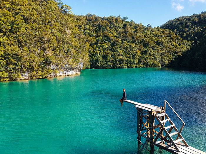 Man sitting over lake on diving platform