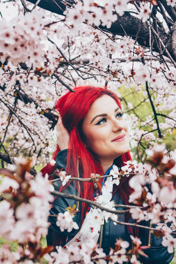 Smiling young woman with redhead sitting by plants in park