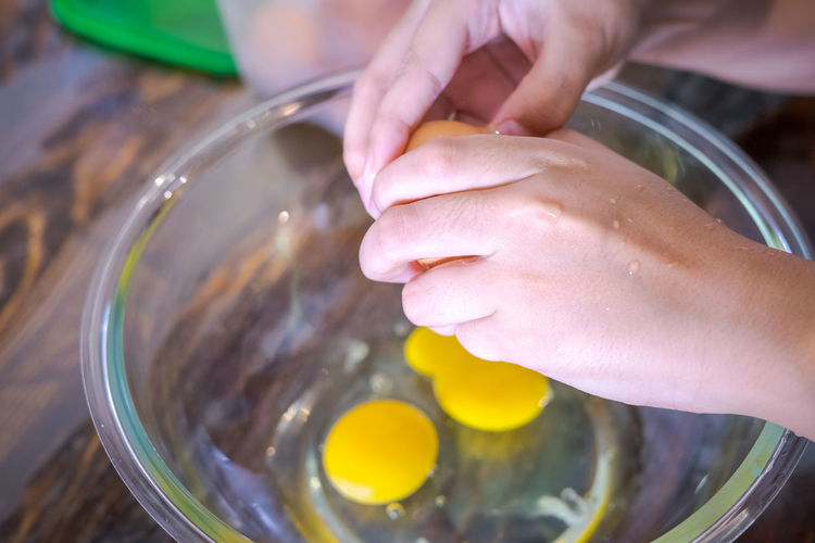 Closeup of a pair of hands cracking an egg into a glass bowl