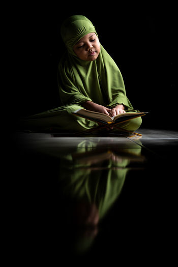 Woman sitting on table against black background