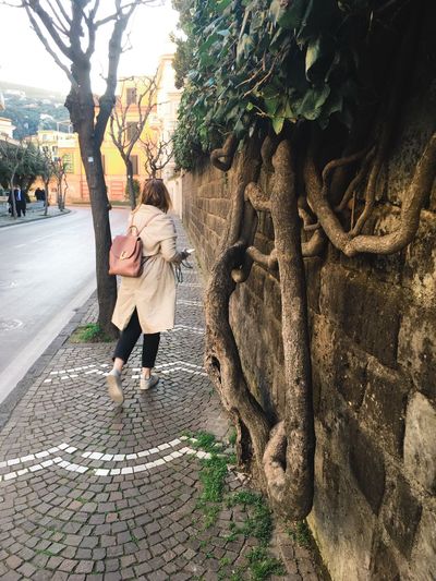 Woman standing by tree trunk in city