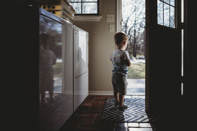 Rear view of silhouette baby boy standing at doorway