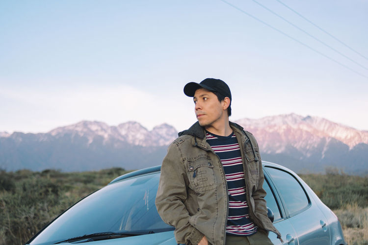 Leaning young man sitting in car admiring the mountainous landscape th