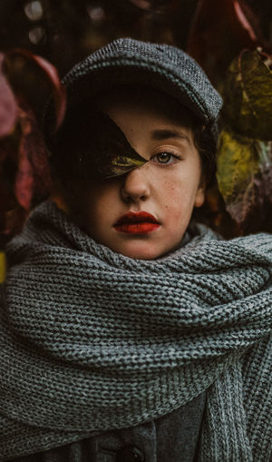Young lady portrait with leaves, scarves laying in the fall