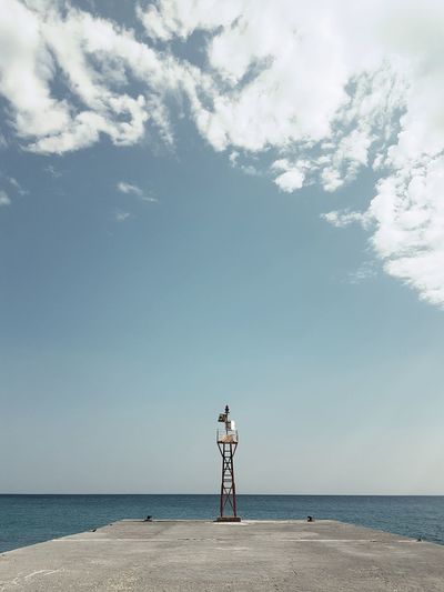 Lookout tower on pier by sea against blue sky