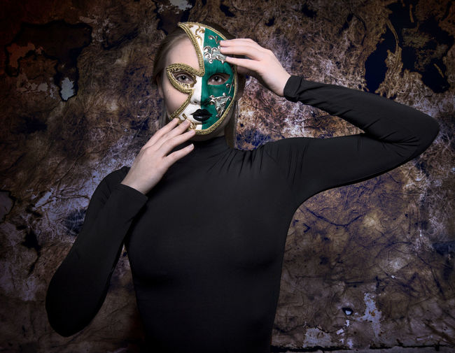 Midsection of person wearing mask standing against wall