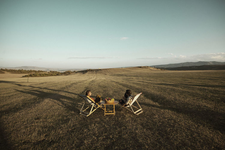 High angle view of friends sitting chairs at field against sky