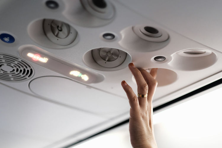 Cropped hand of woman pressing buttons in airplane