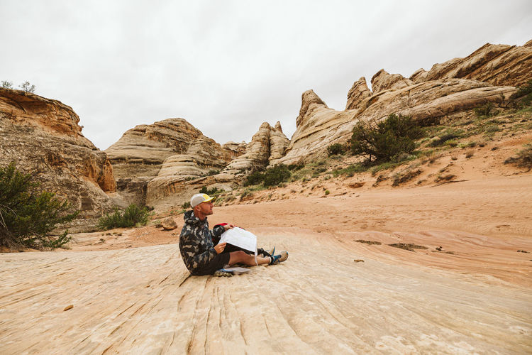 Hiker in camo jacket checks his map in a desert arroyo basin