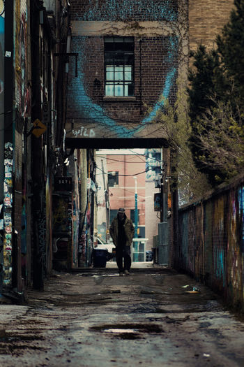 Rear view of man walking on street amidst buildings