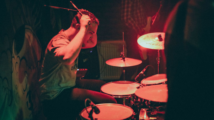 Side view of man playing drum in concert