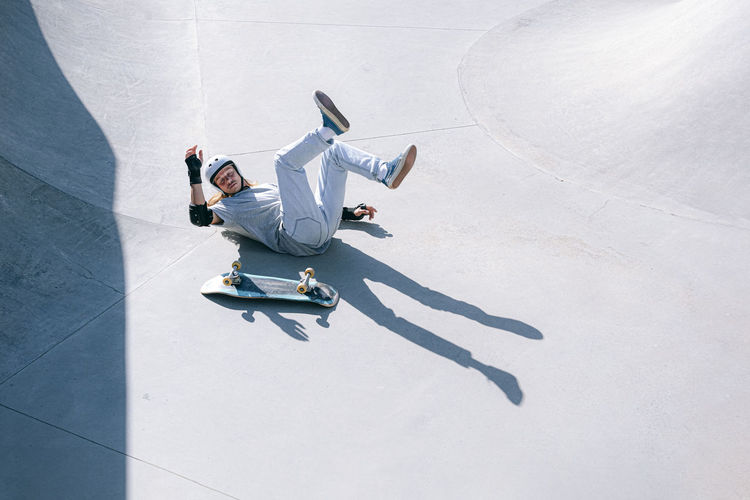 Skateboarder falling in skatepark on sunny day