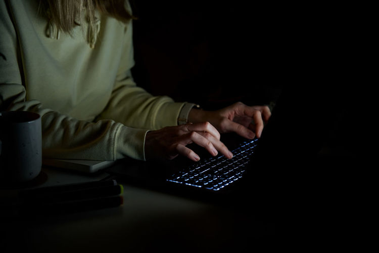 Anonymous woman working on laptop at night