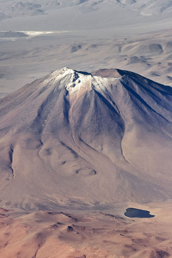 Aerial photography of the andes, brown landscape and desert with a volcano and a lagoon