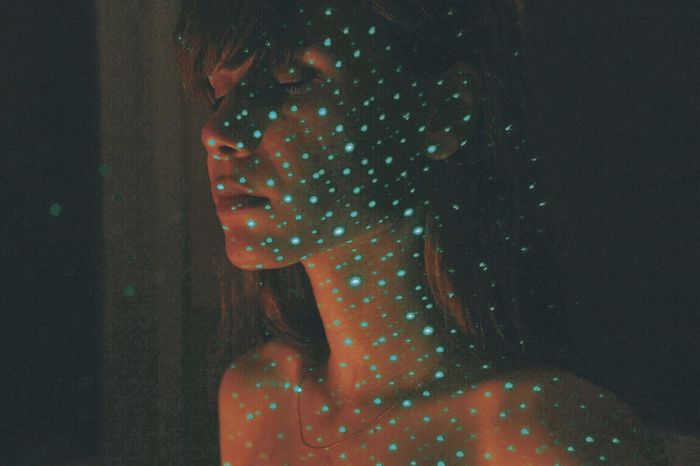 Blue light falling on shirtless young woman in darkroom