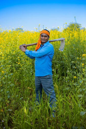 Portrait of farmer holding equipment while standing in farm